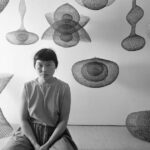 Porträt der japanisch-amerikanischen Künstlerin Ruth Asawa, wie sie inmitten mehrerer ihrer aus Drahtschlingen gefertigten Skulpturen auf dem Boden kniet, November 1954, Detail, Foto: Nat Farbman/The LIFE Picture Collection/Shutterstock, Artwork © 2025 Ruth Asawa Lanier, Inc., Courtesy David Zwirner