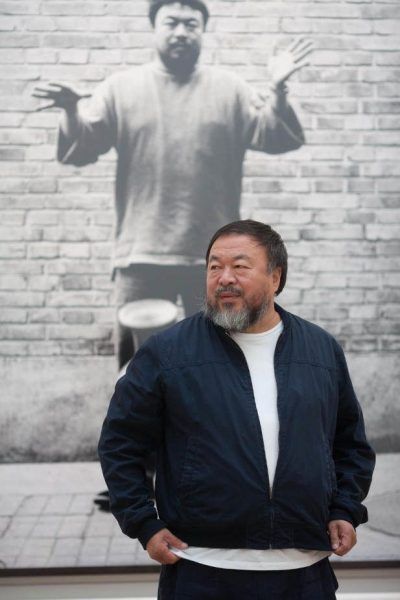 Ai Weiwei with one of his photographs from Dropping a Han Dynasty Urn, Royal Academy of Arts, 2015. Photo courtesy of Royal Academy of Arts, London. Photography © Dave Parry.